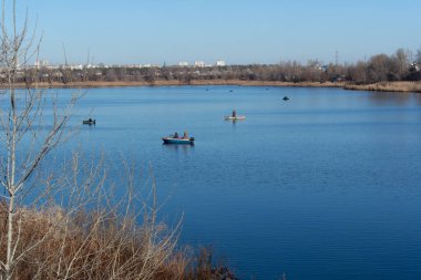Teknelerdeki balıkçılar. Göl manzaralı. Nehrin mavi suyu. Elinde olta olan bir balıkçı. balıkçılık. 