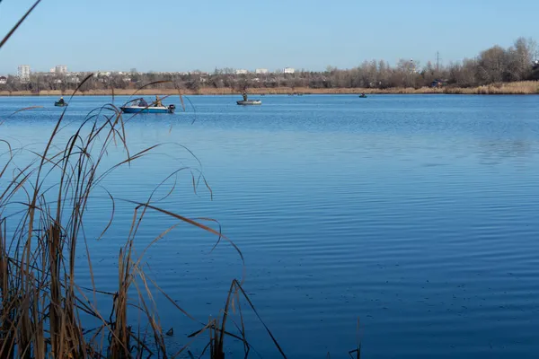 Teknelerdeki balıkçılar. Göl manzaralı. Nehrin mavi suyu. Elinde olta olan bir balıkçı. balıkçılık. 