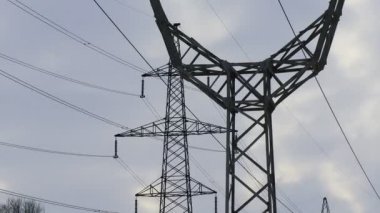 Güç iletim hatları. Elektrik direkleri ve telleri. Günbatımında yüksek voltajlı elektrik hatları, yüksek voltajlı elektrik iletim kulesi. Yüksek voltaj kuleleri uzak mesafeden enerji sağlıyor..