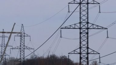 Güç iletim hatları. Elektrik direkleri ve telleri. Günbatımında yüksek voltajlı elektrik hatları, yüksek voltajlı elektrik iletim kulesi. Yüksek voltaj kuleleri uzak mesafeden enerji sağlıyor..