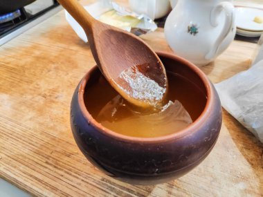 Bal ve kaşık. Bal kaşıktan cam kaseye dökülüyor, masaya, yakın plan. Manuka bal kaşığı altın sıvı süper yiyeceğe batırılmış ahşap arka planda. Dökülen bir damla kaşıkla.