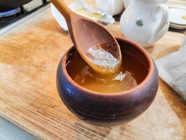 Bal ve kaşık. Bal kaşıktan cam kaseye dökülüyor, masaya, yakın plan. Manuka bal kaşığı altın sıvı süper yiyeceğe batırılmış ahşap arka planda. Dökülen bir damla kaşıkla.