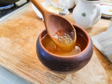 Bal ve kaşık. Bal kaşıktan cam kaseye dökülüyor, masaya, yakın plan. Manuka bal kaşığı altın sıvı süper yiyeceğe batırılmış ahşap arka planda. Dökülen bir damla kaşıkla.