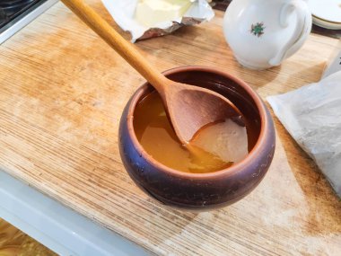 Bal ve kaşık. Bal kaşıktan cam kaseye dökülüyor, masaya, yakın plan. Manuka bal kaşığı altın sıvı süper yiyeceğe batırılmış ahşap arka planda. Dökülen bir damla kaşıkla.