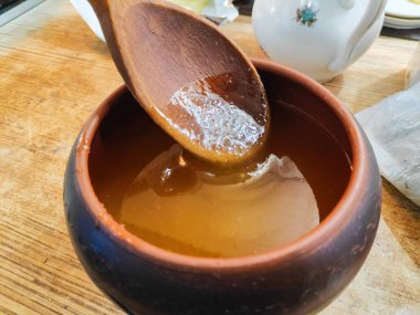 Bal ve kaşık. Bal kaşıktan cam kaseye dökülüyor, masaya, yakın plan. Manuka bal kaşığı altın sıvı süper yiyeceğe batırılmış ahşap arka planda. Dökülen bir damla kaşıkla.