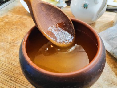 Bal ve kaşık. Bal kaşıktan cam kaseye dökülüyor, masaya, yakın plan. Manuka bal kaşığı altın sıvı süper yiyeceğe batırılmış ahşap arka planda. Dökülen bir damla kaşıkla.