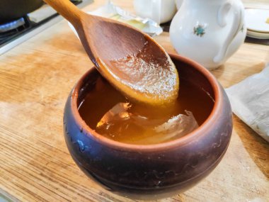 Bal ve kaşık. Bal kaşıktan cam kaseye dökülüyor, masaya, yakın plan. Manuka bal kaşığı altın sıvı süper yiyeceğe batırılmış ahşap arka planda. Dökülen bir damla kaşıkla.