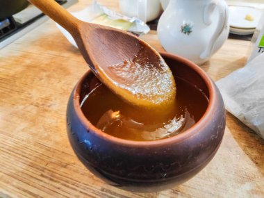 Bal ve kaşık. Bal kaşıktan cam kaseye dökülüyor, masaya, yakın plan. Manuka bal kaşığı altın sıvı süper yiyeceğe batırılmış ahşap arka planda. Dökülen bir damla kaşıkla.