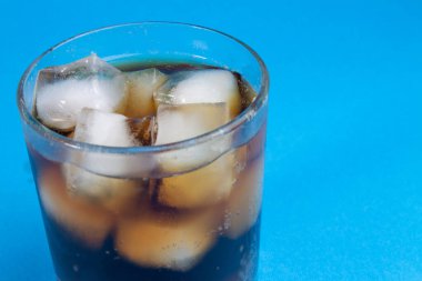 Kola ve buz bir bardakta. Karbonatlı içecek. Beyaza izole edilmiş buzlu tatlı karbonatlı içecekler. Kırpma yolu ile. Buzlu ve köpüklü kolanın arka planı.