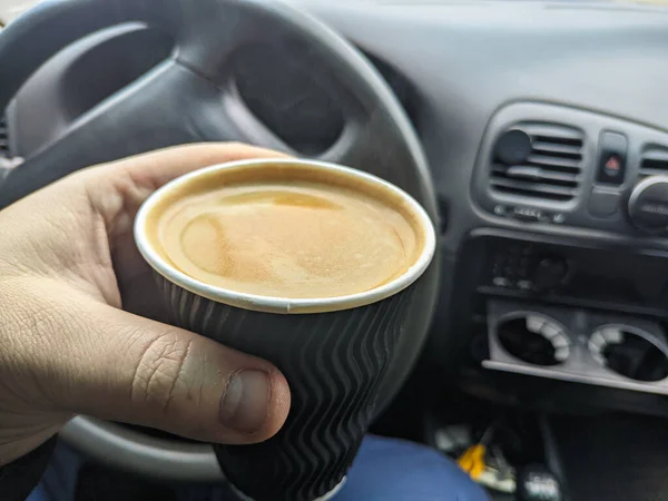 車の中のコーヒー 男は車の中でコーヒーペーパーカップを保持 コーヒーは旅行者の友人です 交通と車両のコンセプト 車を運転しながらコーヒーを飲む男 コーヒーブレイク — ストック写真