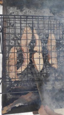 cooking fish on fire. grilled fish. Grilled mackerel fish with smoke on a charcoal barbecue grill. Hot fish on a grilling pan. Grilled fish with spices on the fire