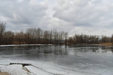 Suyla birlikte kış manzarası. Panorama Gölü 'nün önünde, bulutlu gökyüzünün ve etrafındaki ağaçların ayna etkisi. Sakin su ve ağaçların ve gökyüzünün yansımaları. Saf kuzey doğası..
