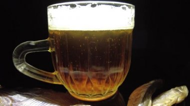 Siyah arka planda bir kupa bira. Bira bardağı. Bira ve balık. Bardakta köpük. Gaz baloncukları. Bir bardak light bira. Koyu bir masada bira bardakları. Soğuk köpüklü biranın foto fincanı..