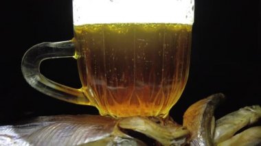 Siyah arka planda bir kupa bira. Bira bardağı. Bira ve balık. Bardakta köpük. Gaz baloncukları. Bir bardak light bira. Koyu bir masada bira bardakları. Soğuk köpüklü biranın foto fincanı..