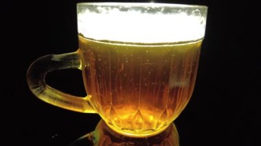 Siyah arka planda bir kupa bira. Bira bardağı. Bira ve balık. Bardakta köpük. Gaz baloncukları. Bir bardak light bira. Koyu bir masada bira bardakları. Soğuk köpüklü biranın foto fincanı..