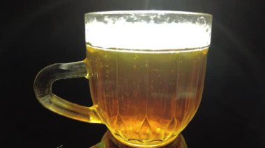 Siyah arka planda bir kupa bira. Bira bardağı. Bira ve balık. Bardakta köpük. Gaz baloncukları. Bir bardak light bira. Koyu bir masada bira bardakları. Soğuk köpüklü biranın foto fincanı..