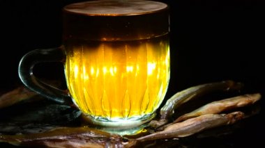 Siyah arka planda bir kupa bira. Bira bardağı. Bira ve balık. Bardakta köpük. Gaz baloncukları. Bir bardak light bira. Koyu bir masada bira bardakları. Soğuk köpüklü biranın foto fincanı..