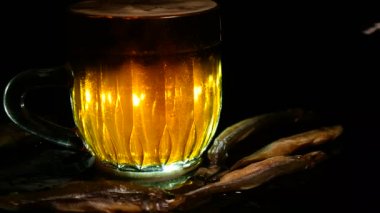 Siyah arka planda bir kupa bira. Bira bardağı. Bira ve balık. Bardakta köpük. Gaz baloncukları. Bir bardak light bira. Koyu bir masada bira bardakları. Soğuk köpüklü biranın foto fincanı..