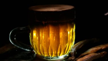 Siyah arka planda bir kupa bira. Bira bardağı. Bira ve balık. Bardakta köpük. Gaz baloncukları. Bir bardak light bira. Koyu bir masada bira bardakları. Soğuk köpüklü biranın foto fincanı..