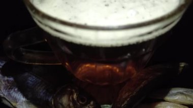 Siyah arka planda bir kupa bira. Bira bardağı. Bira ve balık. Bardakta köpük. Gaz baloncukları. Bir bardak light bira. Koyu bir masada bira bardakları. Soğuk köpüklü biranın foto fincanı..