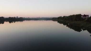 Hava aracı videosundan şafak söküyor. İnsansız hava aracı nefes kesici kırsal alan ve tarım arazisi üzerinde uçuyor. Sinematik hava çekimi. Gün batımında kuşbakışı akan kıvrımlı nehir.