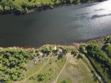 Yukarıdan suyla kaplı bir manzara. Kumlu sahil ve dalgalı okyanus manzarası. Fotoğraf yukarıdan bir dron tarafından çekildi. Doğa manzarası. Yeşil çimenli bir ormanın havadan görünüşü.