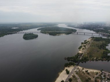 Yukarıdan suyla kaplı bir manzara. Kumlu sahil ve dalgalı okyanus manzarası. Fotoğraf yukarıdan bir dron tarafından çekildi. Doğa manzarası. Yeşil çimenli bir ormanın havadan görünüşü.