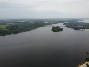 Yukarıdan suyla kaplı bir manzara. Kumlu sahil ve dalgalı okyanus manzarası. Fotoğraf yukarıdan bir dron tarafından çekildi. Doğa manzarası. Yeşil çimenli bir ormanın havadan görünüşü.