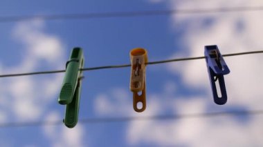 İpteki eski kazıklar. Keten bir ipe bağlanmış eski bir mandal. Evde çalış, çamaşır yıka, çarşaf kurula. Eski Kirli Mavi ve Pembe elbise askısı. Arka planda izole edilmiş bir halat.