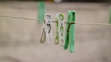 İpteki eski kazıklar. Keten bir ipe bağlanmış eski bir mandal. Evde çalış, çamaşır yıka, çarşaf kurula. Eski Kirli Mavi ve Pembe elbise askısı. Arka planda izole edilmiş bir halat.