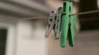 İpteki eski kazıklar. Keten bir ipe bağlanmış eski bir mandal. Evde çalış, çamaşır yıka, çarşaf kurula. Eski Kirli Mavi ve Pembe elbise askısı. Arka planda izole edilmiş bir halat.