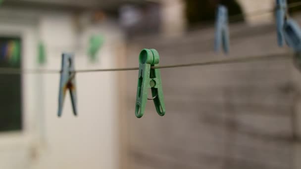 绳子上的老钉子 一个旧的复古衣针木制在亚麻绳上 房子上的工作 干亚麻布 旧的脏蓝色和粉色衣服钉在绳子上 电线与模糊的背景隔离 — 图库视频影像