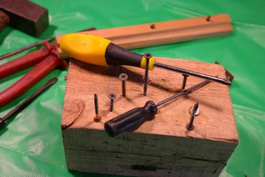 Tornavidayla çevirme. Ekip şoförü ve vidaları çalışıyor. Atölyede çalışıyorum. Tornavida metal çelik cıvatayı vidaladı. Anahtar, cıvata, vida ve fındık. Marangozluk atölyesinde ahşapla çalışmak..