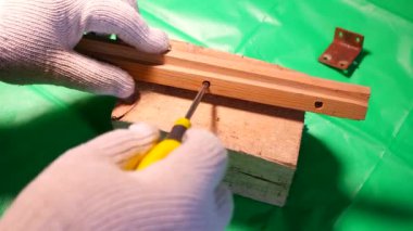 Tornavidayla çevirme. Ekip şoförü ve vidaları çalışıyor. Atölyede çalışıyorum. Tornavida metal çelik cıvatayı vidaladı. Anahtar, cıvata, vida ve fındık. Marangozluk atölyesinde ahşapla çalışmak..