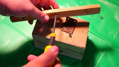 Tornavidayla çevirme. Ekip şoförü ve vidaları çalışıyor. Atölyede çalışıyorum. Tornavida metal çelik cıvatayı vidaladı. Anahtar, cıvata, vida ve fındık. Marangozluk atölyesinde ahşapla çalışmak..