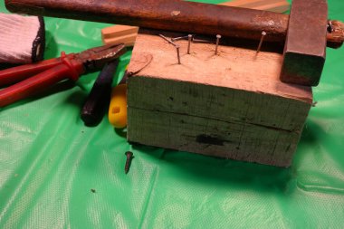 Çekiç çivisi. Çekiç ve çivi kullanarak. Tahtaya çivi çakmaya yakın. Kırmızı flanel gömlek, kot pantolon ve kumaş eldiven giyen bir marangoz tahta tahtaları çiviliyor..