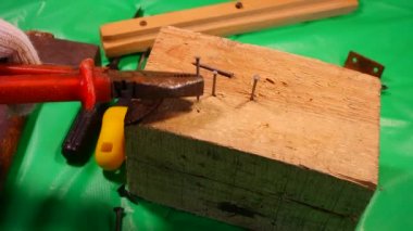 Çekiç çivisi. Çekiç ve çivi kullanarak. Tahtaya çivi çakmaya yakın. Kırmızı flanel gömlek, kot pantolon ve kumaş eldiven giyen bir marangoz tahta tahtaları çiviliyor..