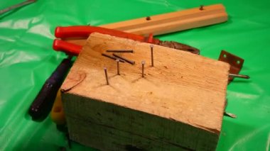 Çekiç çivisi. Çekiç ve çivi kullanarak. Tahtaya çivi çakmaya yakın. Kırmızı flanel gömlek, kot pantolon ve kumaş eldiven giyen bir marangoz tahta tahtaları çiviliyor..