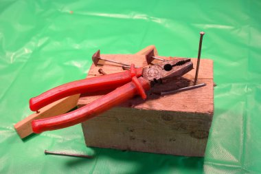 Penseyle çivi söküyorum. Marangoz kerpeteni kurtarma, yardım konsepti teması. İşçi, eğri çiviyi penseyle söküyor. Ahşap işçilerinin elleri kapalı..