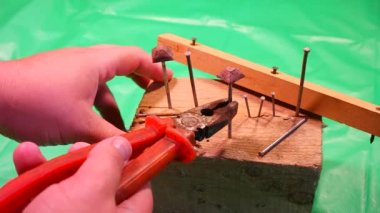 Penseyle çivi söküyorum. Marangoz kerpeteni kurtarma, yardım konsepti teması. İşçi, eğri çiviyi penseyle söküyor. Ahşap işçilerinin elleri kapalı..