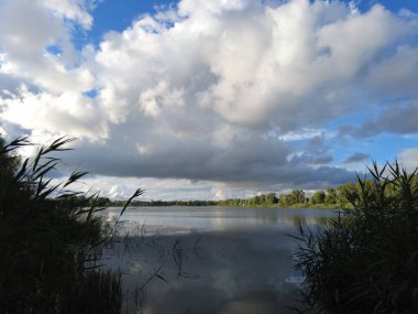 Su ve bulutlarla dolu güzel bir manzara. Ukrayna. Ukrayna manzarası. Güzel bir akşam manzarası. Doğal duvar kağıdı. Geniş nehir. Nehirde bir yaz akşamı.