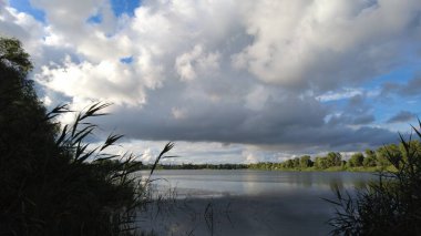 Su ve bulutlarla dolu güzel bir manzara. Ukrayna. Ukrayna manzarası. Güzel bir akşam manzarası. Doğal duvar kağıdı. Geniş nehir. Nehirde bir yaz akşamı.