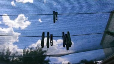 clothespins. Plastic clothespins hang in a row on the rope. Rope outdoors, on a blurred background in a sunny garden. clothesline on the street. Clothespins. old pegs on a rope.