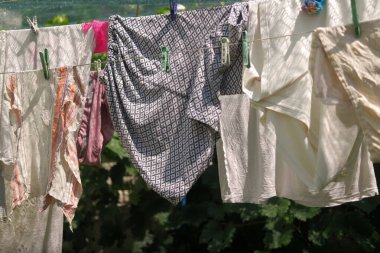 Giysiler ipte. Elbiseleri çamaşır mandallarıyla iple yıka. Çamaşır gününde dışarıda temiz kıyafetlerle halat.