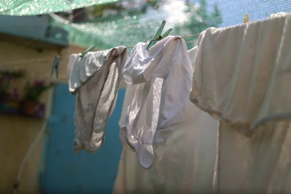 clothes on a rope. Wash clothes on a rope with clothespins on background. Rope with clean clothes outdoors on laundry day