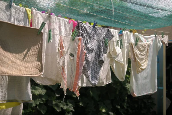 clothes on a rope. Wash clothes on a rope with clothespins on background. Rope with clean clothes outdoors on laundry day