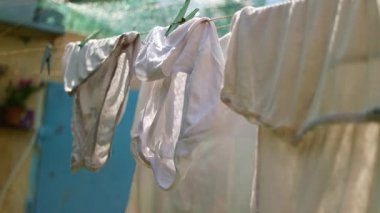 Giysiler ipte. Elbiseleri çamaşır mandallarıyla iple yıka. Çamaşır gününde dışarıda temiz kıyafetlerle halat.