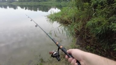 Man fishing in river, first person fishing. Fisherman with rod, spinning reel on the river bank. Sunrise. The concept of a rural getaway.Fisherman holds fishing rod close-up in the first person
