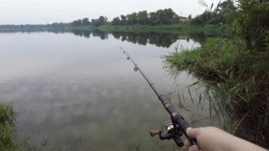 Man fishing in river, first person fishing. Fisherman with rod, spinning reel on the river bank. Sunrise. The concept of a rural getaway.Fisherman holds fishing rod close-up in the first person
