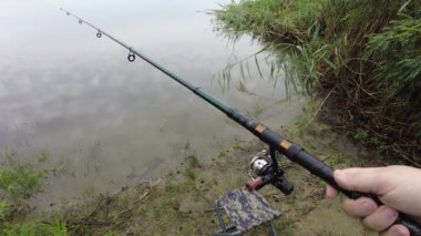 Man fishing in river, first person fishing. Fisherman with rod, spinning reel on the river bank. Sunrise. The concept of a rural getaway.Fisherman holds fishing rod close-up in the first person